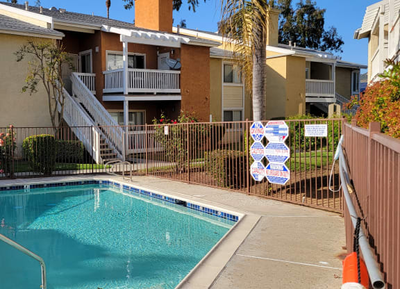 Sparkling swimming pool nestled between apartment buildings in lush garden courtyard at The Cove at Bear Valley in Escondido, California.