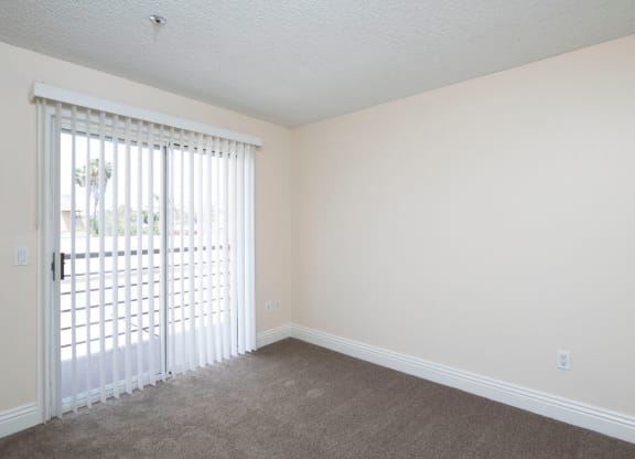 Carpeted bedroom with balcony at the Atrium Apartments in San Diego, California.