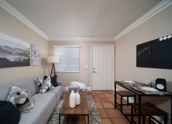 Living room with crown molding and Saltillo tile floors in model unit at the Atrium Apartments in San Diego, California.