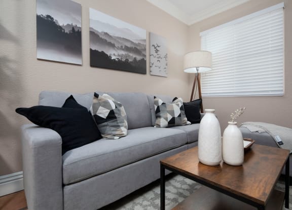 Living room of model unit with Saltillo tile flooring, crown molding and custom window blinds at the Atruim Apartments in San Diego, California.