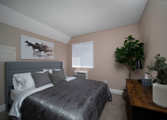 Bedroom in model unit with berber carpet and custom window blinds at the Atrium Apartments in San Diego, California.