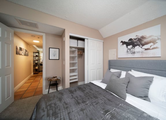 Bedroom in model unit showing spacious closets and berber carpet at the Atrium Apartments in San Diego, California.