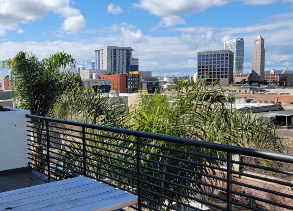 Patio tables, planters, and skyline view of San Diego at Atrium Apartments.