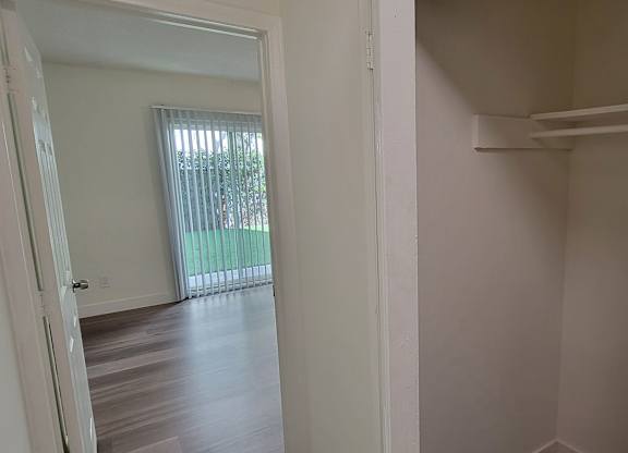 A white door is open to a room with a window and a balcony.