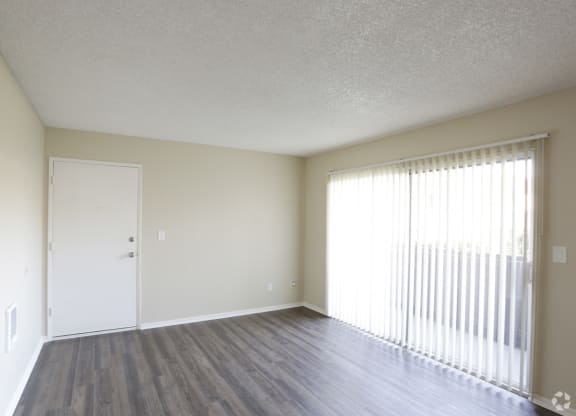 Living room with front door and sliding glass doors to private porch at Villa Pacific Apartments in Oceanside, California.