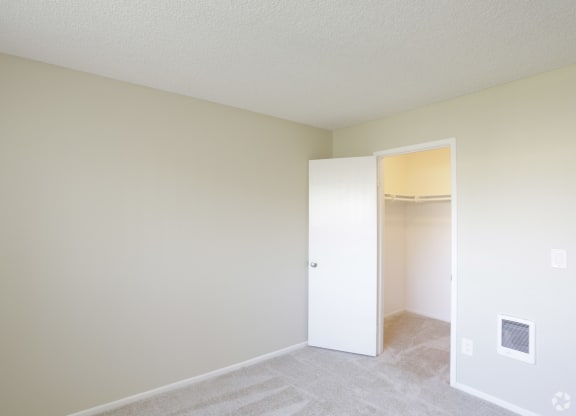 Carpeted bedroom with walk-in closet at Villa Pacific Apartments in Oceanside, California.