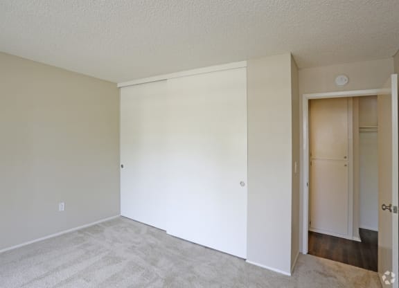 Carpeted bedroom with large closet at Villa Pacific Apartments in Oceanside, California.