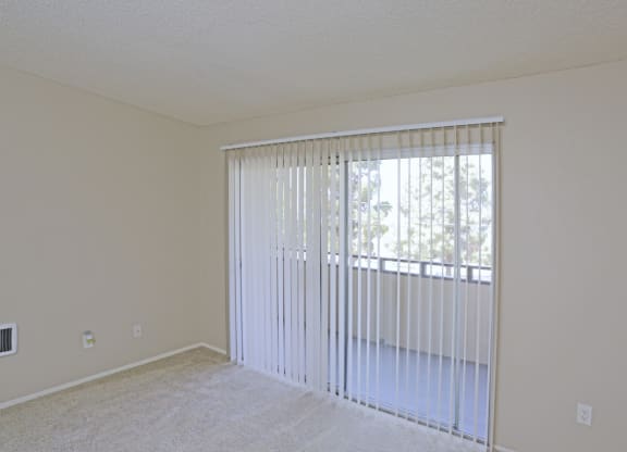 Carpeted master bedroom with sliding glass door to private porch at Villa Pacific Apartments in Oceanside, California.