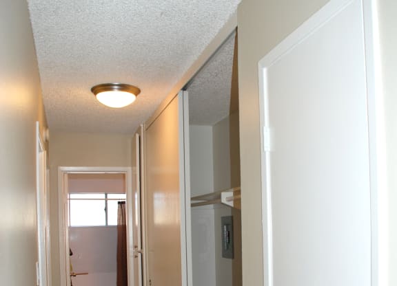 Carpeted bedroom hallway with closets and bathroom at Villa Pacific Apartments in Oceanside, California.