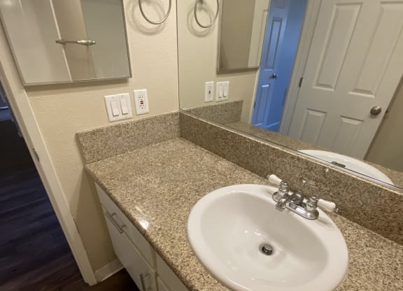 Bathroom with plank style flooring and vanity with white cabinets at Villa Pacific Apartments in Oceanside, California.