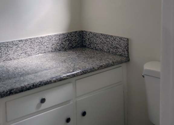A white toilet sits next to a window in a bathroom.