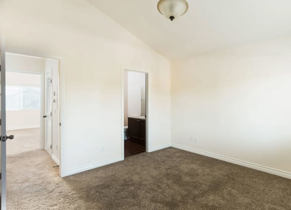 Large carpeted bedrooms with shared bathroom and cathedral ceilings at The Nines Townhomes in Escondido, California.