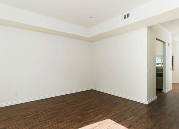 Living room with wood style laminate flooring, windows and access to private porch at The Nines Townhomes in Escondido, California.