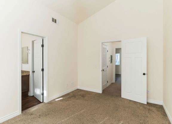 Carpeted bedroom with cathedral ceinling and bathroom at The Nines Townhomes in Escondido, California.