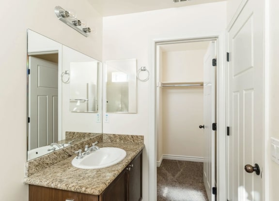 Shared bathroom with granite slab vanity top and upgraded fixtures at The Nines Townhomes in Escondido, California.