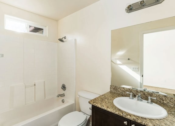 Bathroom with granite slab vanity counter top, white fixtures, upgraded faucets, and privace window for natural light at The Nines Townhomes in Escondido, California.