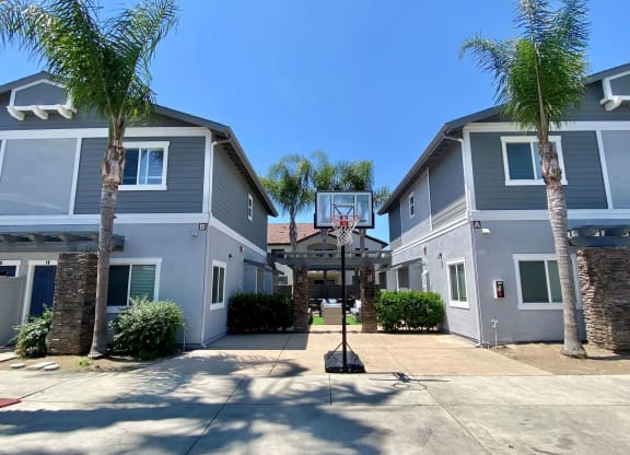 Community area with backetball hoop and sitting area in background at The Nines Townhomes in Escondido, California.