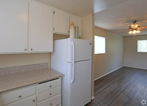 A white refrigerator in a kitchen with white cabinets and a counter.