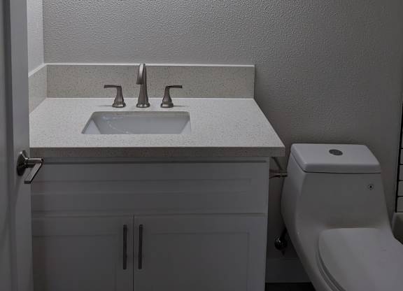 Lots of bathroom lighting and white fixtures at The Hardison Apartments in Pasadena, California.