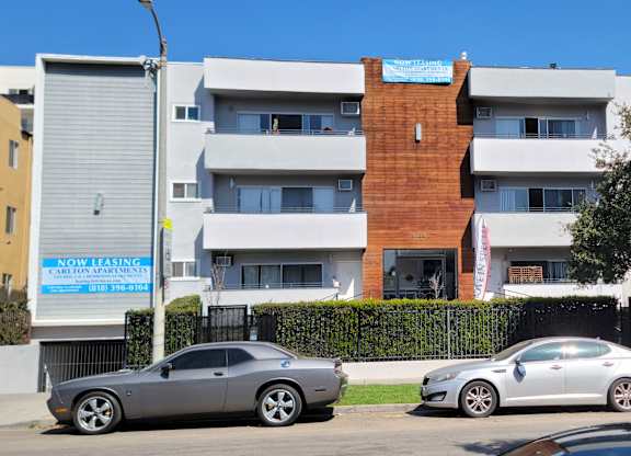 Two cars are parked in front of a multi-story building.