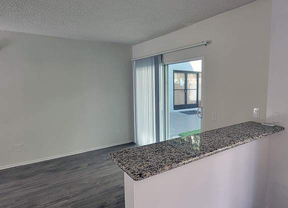 A room with a granite countertop and a sliding glass door.