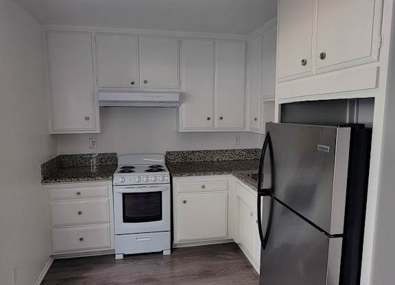 A kitchen with white cabinets and a black fridge.