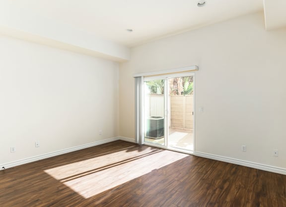 Living room with wood style laminate floors and sliding glass doors to private porch at The Nines Townhomes in Escondido, California.