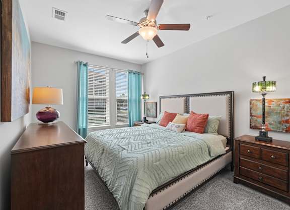 A bedroom with a bed, nightstand, and a ceiling fan.