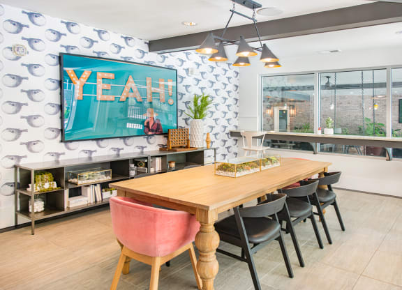a dining area with a wooden table and chairs and a large flat screen tv on the wall