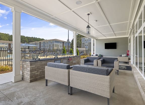 a covered patio with couches and chairs and a wall of windows
