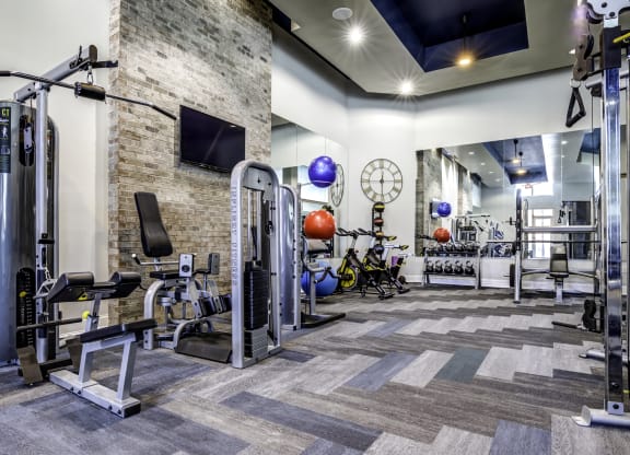 a spacious fitness center with cardio equipment and a large clock on the wall