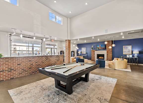 A pool table is in the middle of a room with a brick wall.