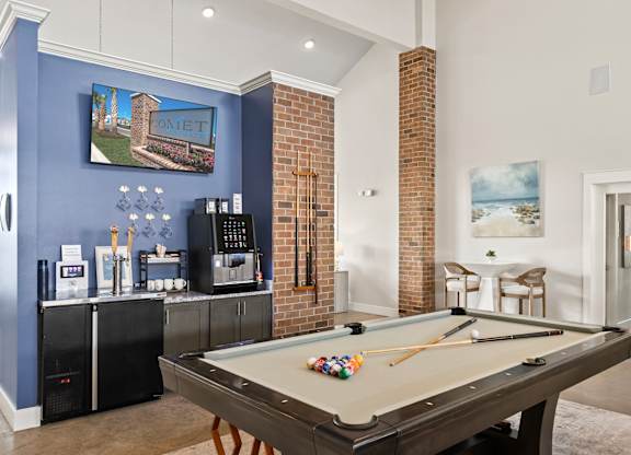 A pool table in a room with a blue wall and a fridge.