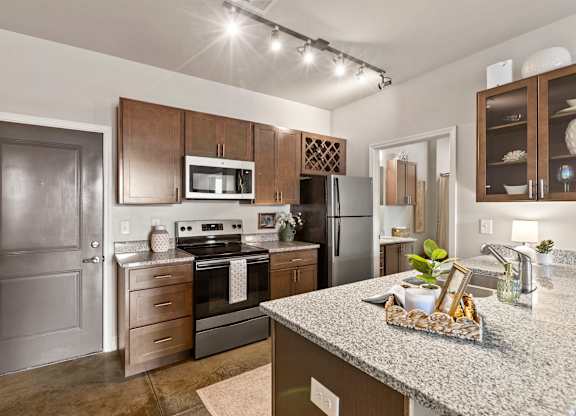 A kitchen with a granite countertop and stainless steel appliances.