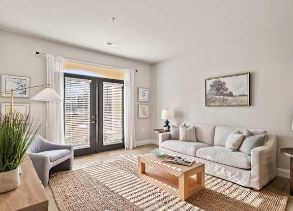 A living room with a grey couch, a coffee table, and a painting on the wall.