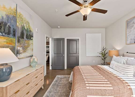 A bedroom with a bed, dresser, and painting on the wall.