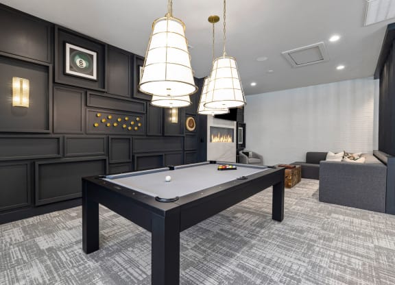 a billiards table in a game room with three lamps