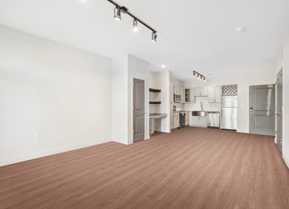 an empty living room and kitchen with a wood floor