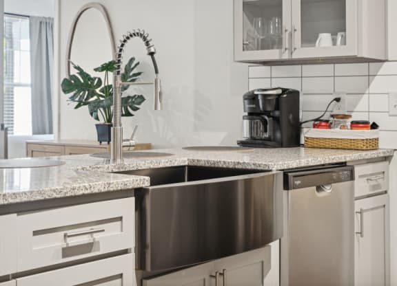 a kitchen with white cabinets and a stainless steel sink