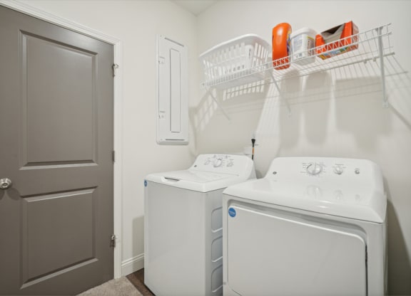 a white laundry room with a white washer and dryer and a gray door