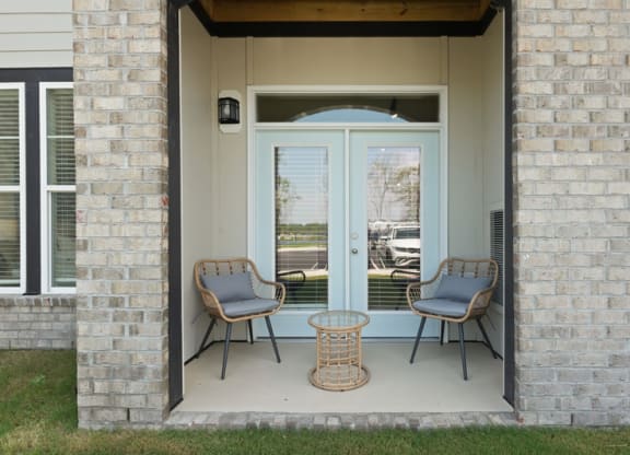 theporch of an apartment with two chairs and a table