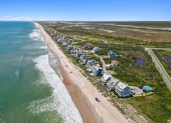A beachfront with houses and people on the sand.