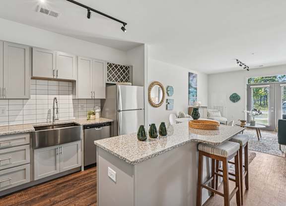 A kitchen with a refrigerator, sink, and bar stools.