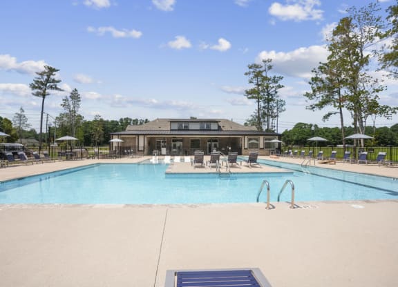 a swimming pool with chairs and a building in the background