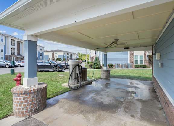 A red fire hydrant is on the left side of a concrete area under a covered walkway.