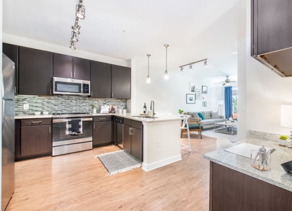 a kitchen and living room with wood flooring and stainless steel appliances