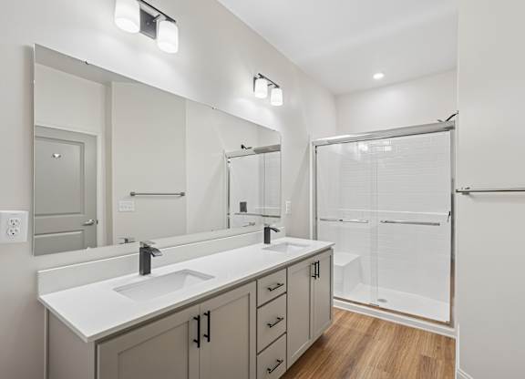 A bathroom with a sink, mirror, and shower.