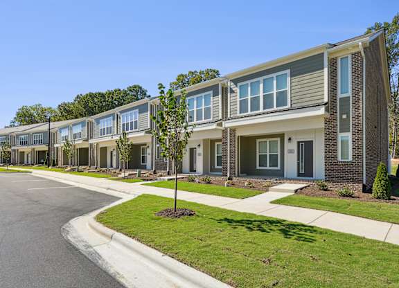 A row of modern houses with a clear blue sky above them.