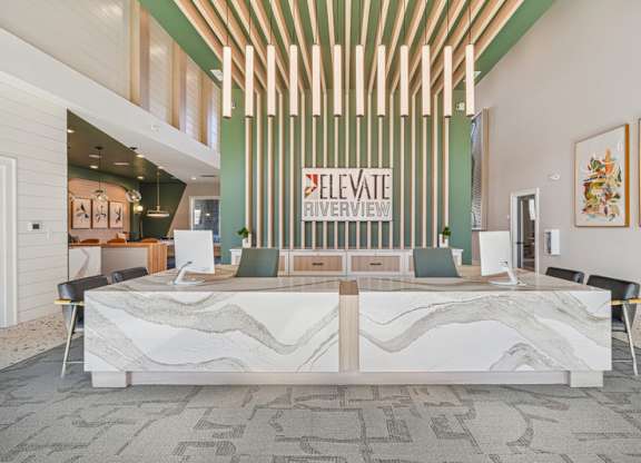 A reception area with a white reception desk and a green wall with a sign that says