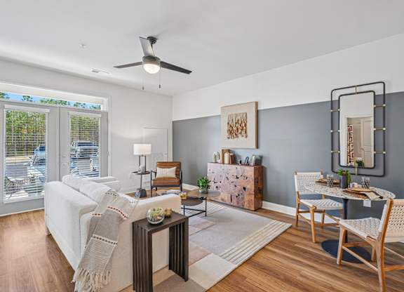 A living room with a white couch, a wooden coffee table, and a dining table set up.